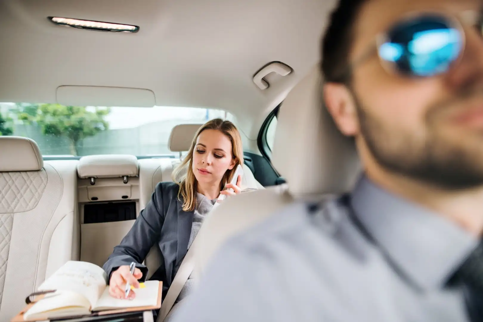 business woman with smartphone sitting on back seat