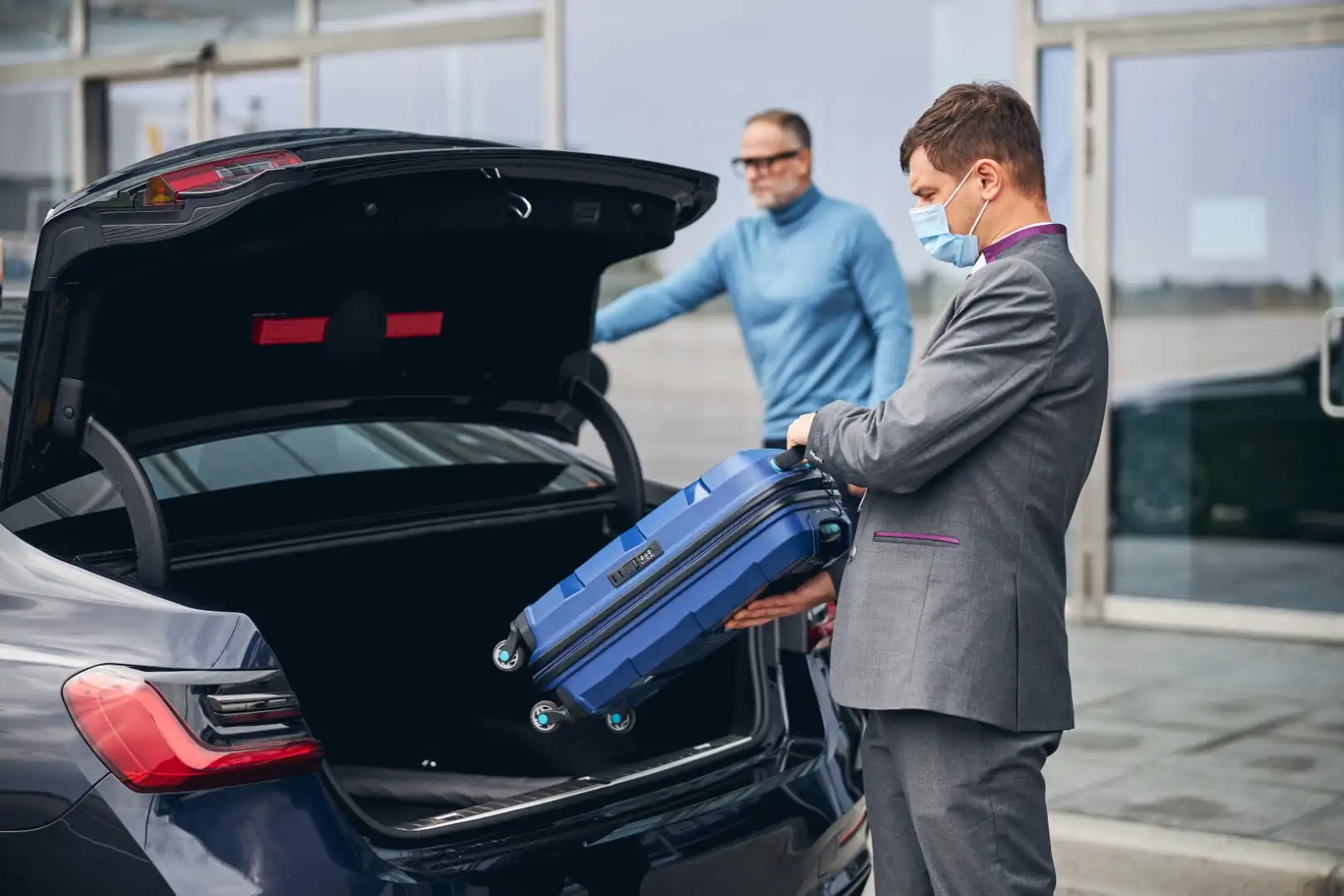 chauffeur standing by the vehicle with the open boot
